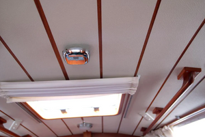 A silver chrome smoke alarm installed on the roof of a campervan. 